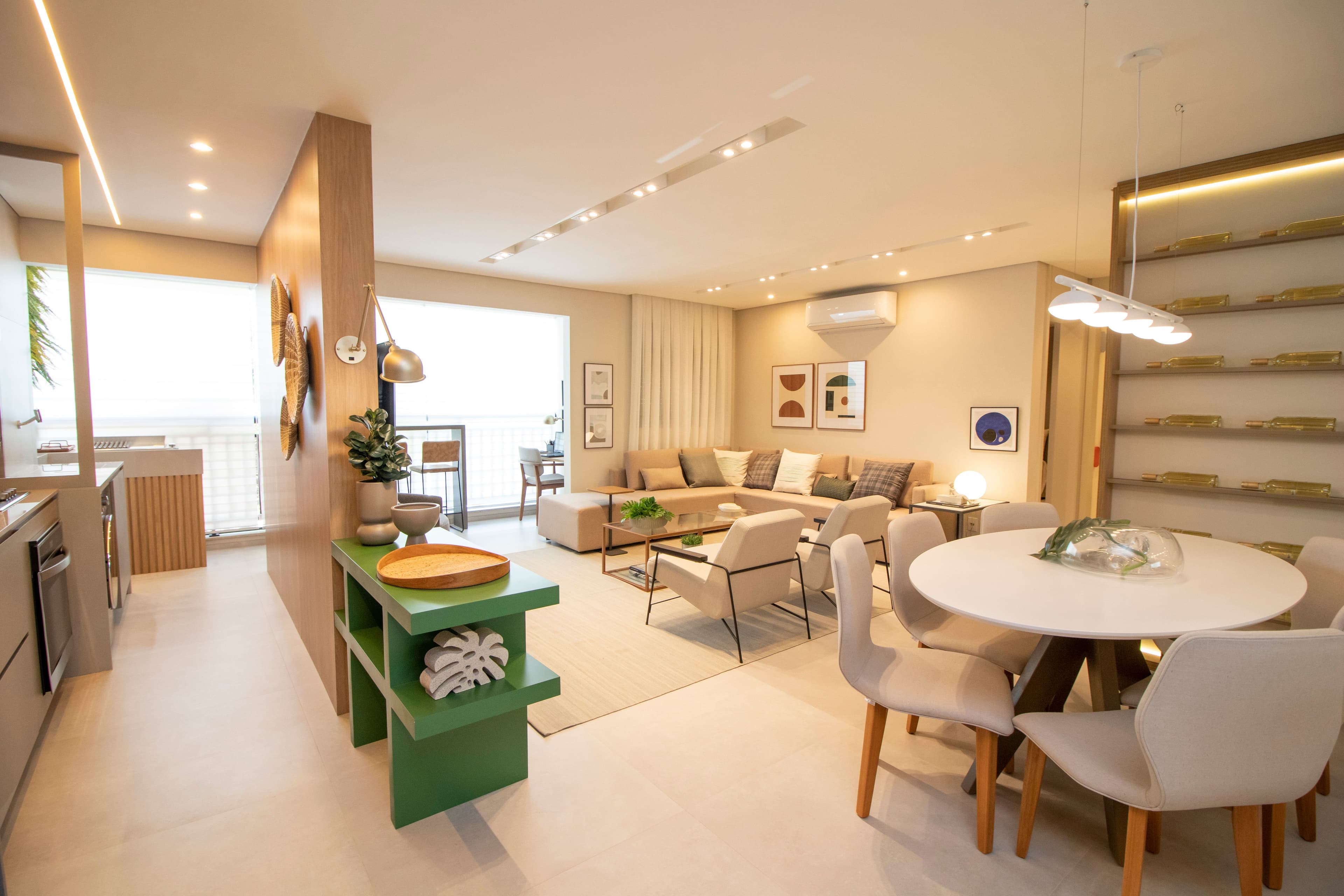 Sala de estar integrada com jantar, sofá bege, mesa de jantar redonda e armários planejados